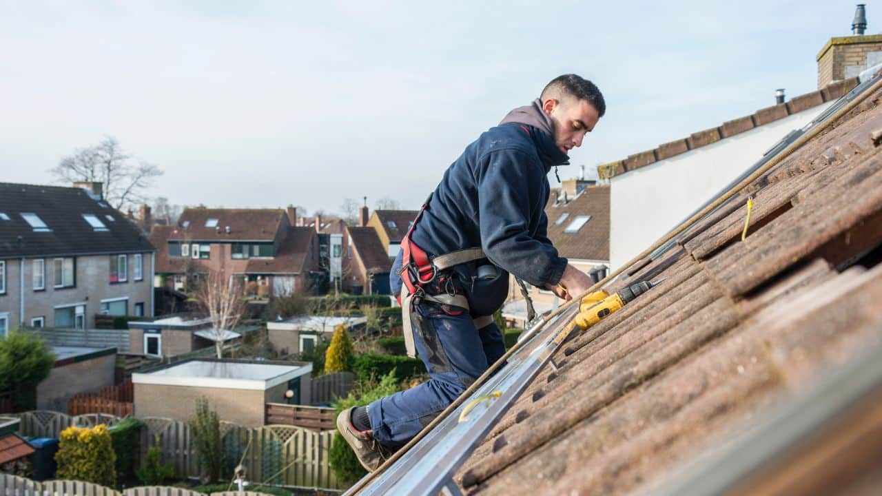 man making the construction for the solar panels high on the roof